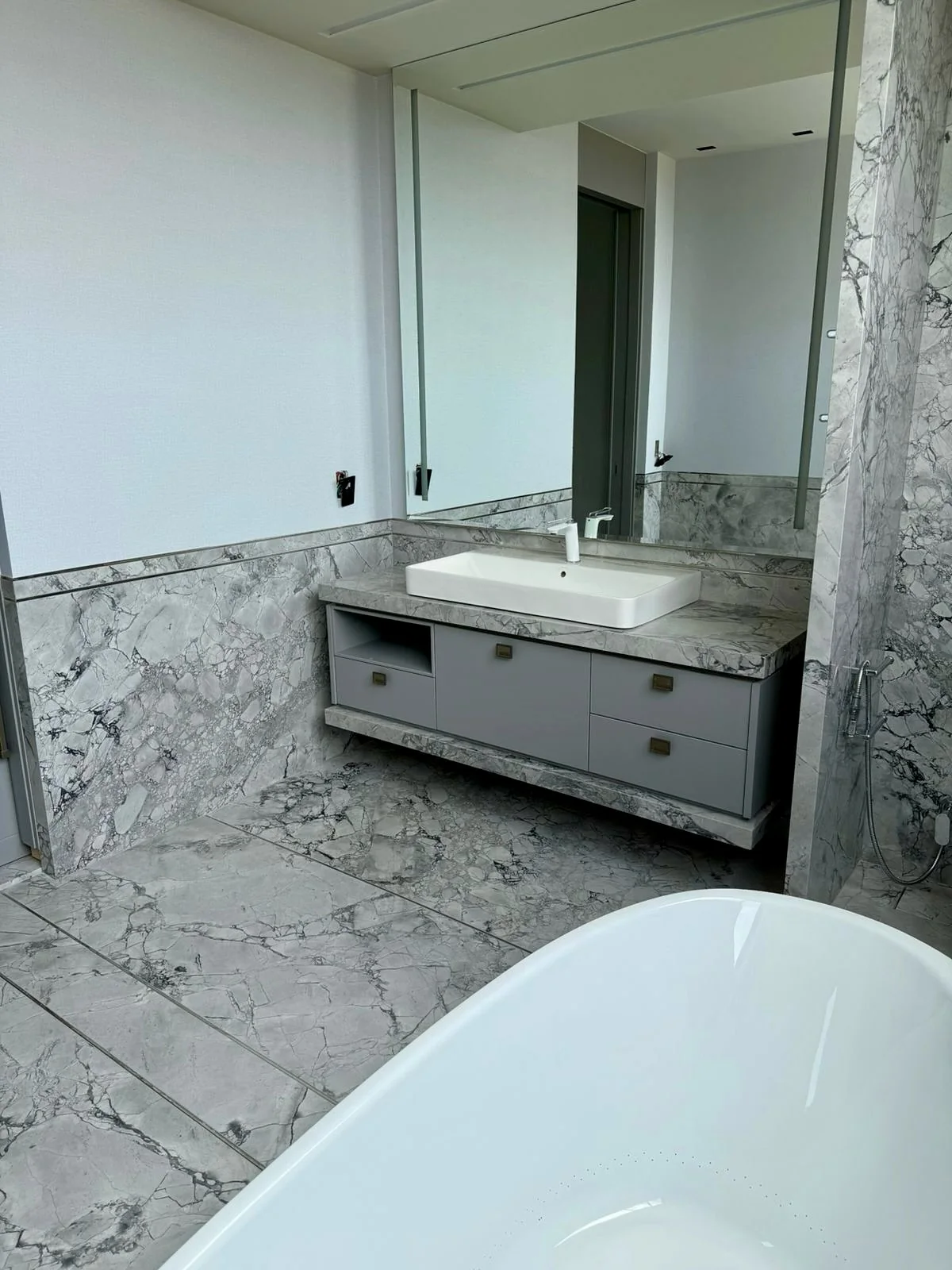 Banheiro com bancada, piso e revestimento de pedra marmorizada